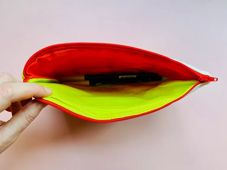 A hand showing lining fabric in red and lime green