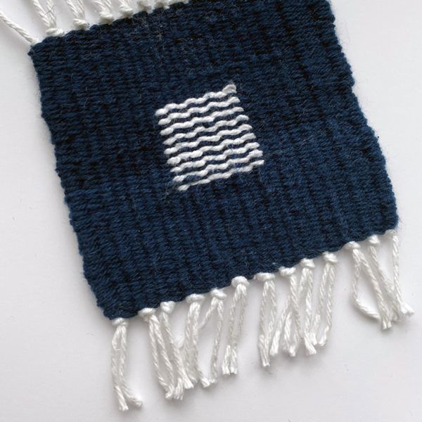 One of the coasters, where the bottom half of the navy yarn is a bit lighter in color than the top half