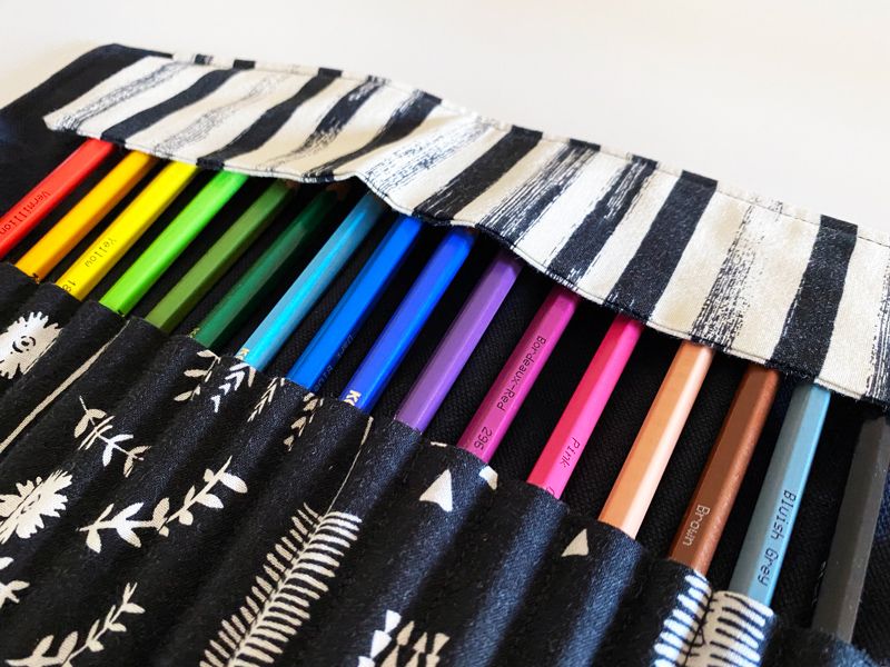 A rainbow array of pencils inserted into the slots, with the protective flap down over their tips.